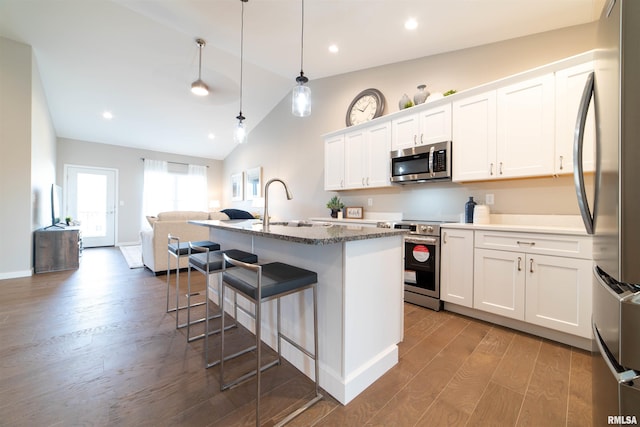 kitchen featuring pendant lighting, sink, appliances with stainless steel finishes, white cabinetry, and an island with sink