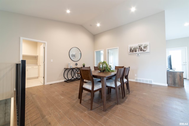 dining area with high vaulted ceiling, plenty of natural light, and light hardwood / wood-style floors