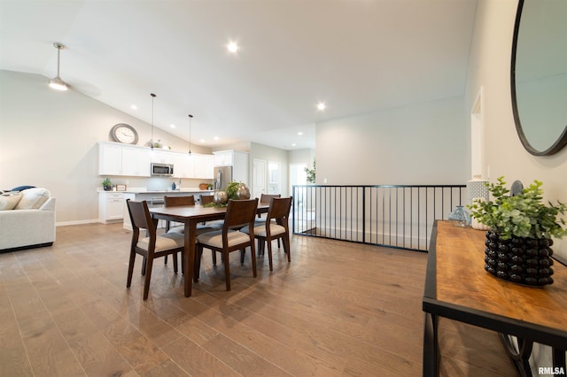 dining room with high vaulted ceiling and light wood-type flooring