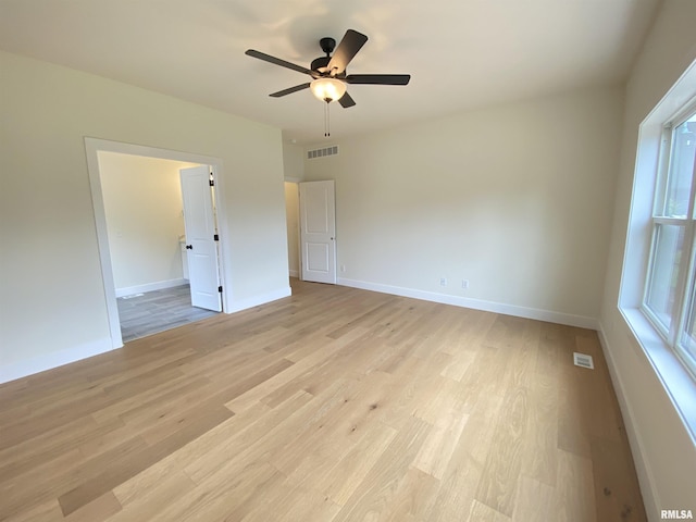 empty room featuring light wood finished floors, baseboards, visible vents, and ceiling fan