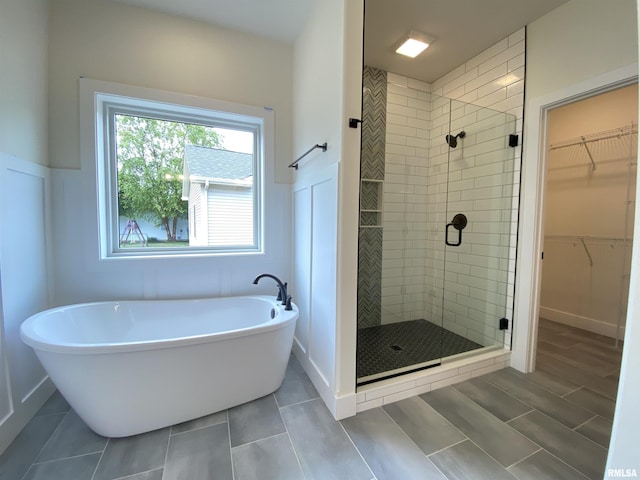 full bath with a shower stall, a spacious closet, baseboards, and a freestanding bath