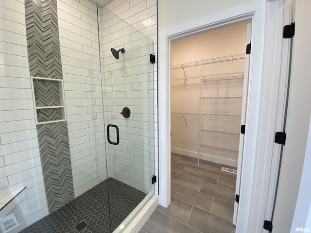 full bath with a stall shower, a spacious closet, and tile patterned floors