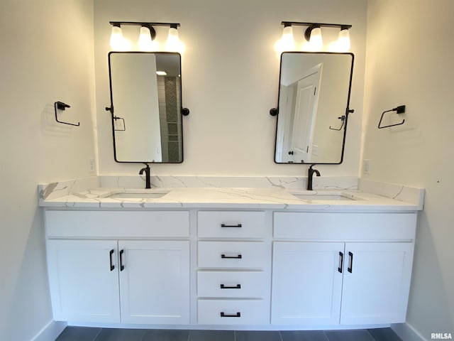 full bathroom featuring a sink, baseboards, and double vanity