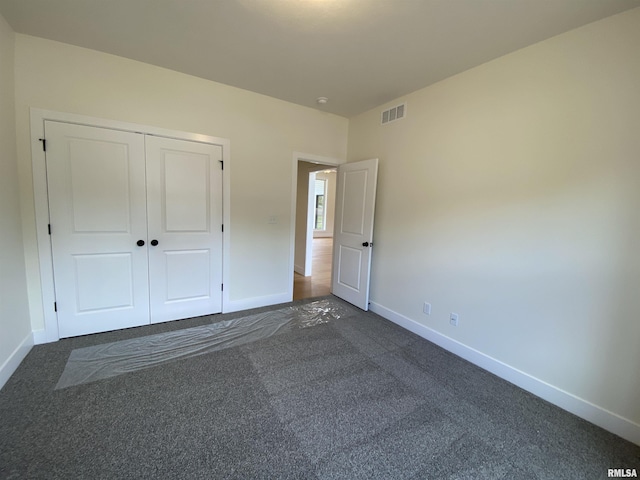 unfurnished bedroom featuring baseboards, visible vents, and dark carpet