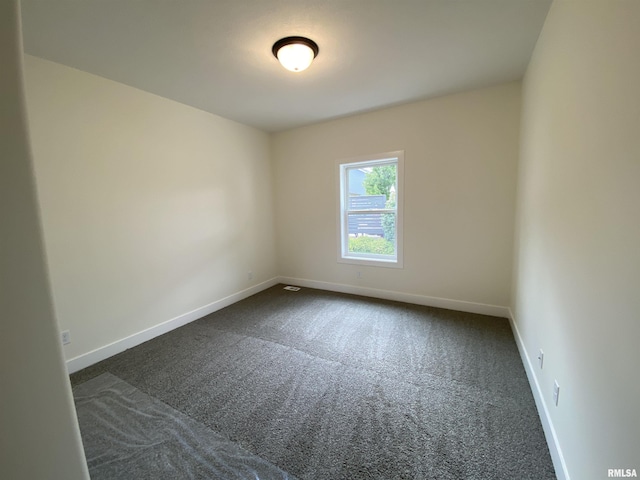 unfurnished room featuring baseboards and dark colored carpet