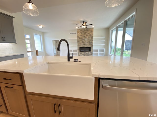 kitchen featuring a fireplace, a sink, visible vents, a healthy amount of sunlight, and stainless steel dishwasher