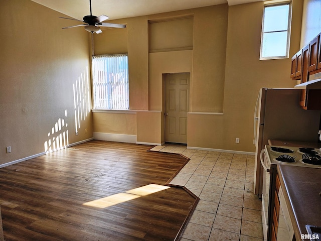 kitchen with ceiling fan, light tile patterned flooring, white range with electric stovetop, and a healthy amount of sunlight