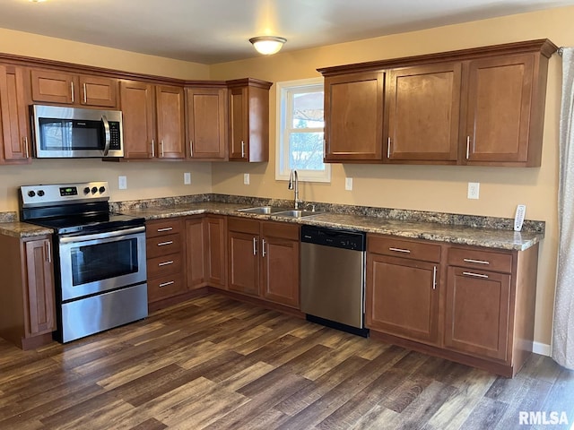 kitchen featuring dark wood-type flooring, stainless steel appliances, dark stone countertops, and sink