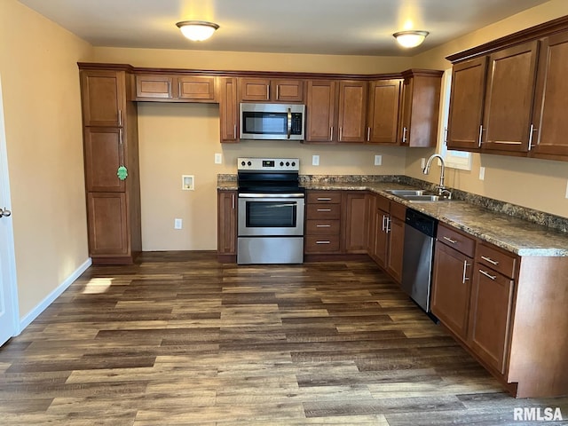 kitchen with dark stone counters, appliances with stainless steel finishes, sink, and dark hardwood / wood-style floors