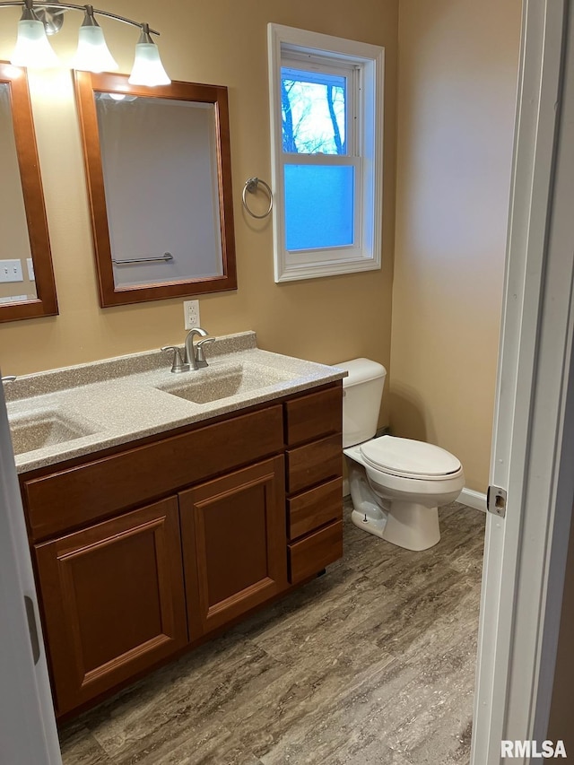 bathroom featuring toilet, hardwood / wood-style flooring, and vanity