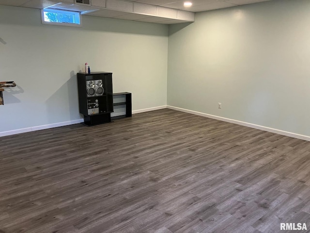 basement with dark wood-type flooring and a paneled ceiling