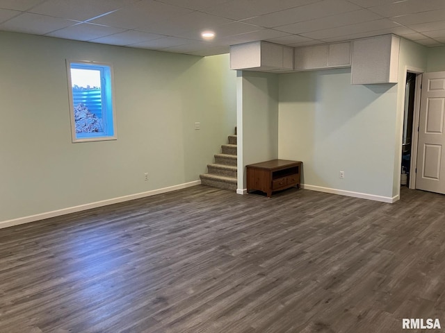 basement with dark wood-type flooring and a paneled ceiling