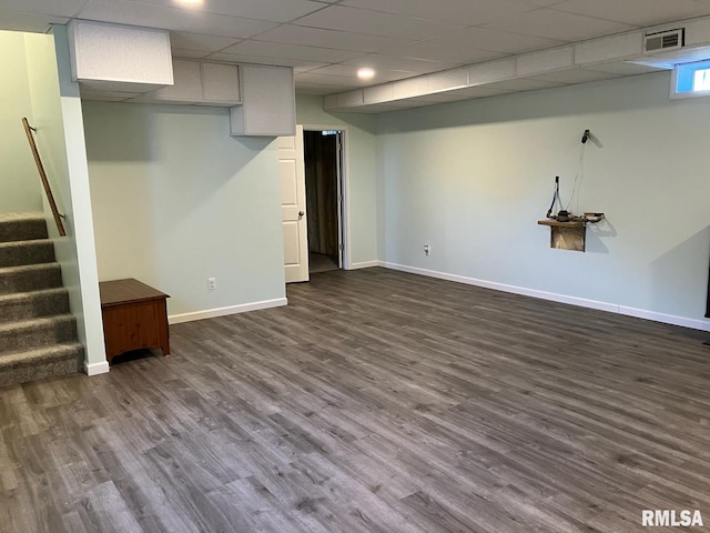 basement featuring a paneled ceiling and dark hardwood / wood-style floors