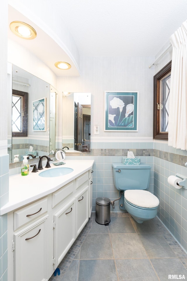 bathroom with tile flooring, tile walls, toilet, and vanity