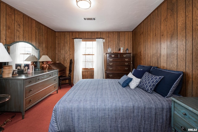 bedroom with dark colored carpet and wood walls