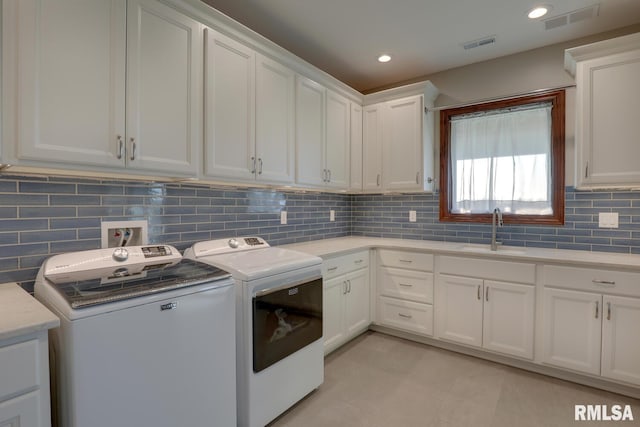 laundry room featuring light tile patterned floors, cabinets, sink, and washing machine and clothes dryer