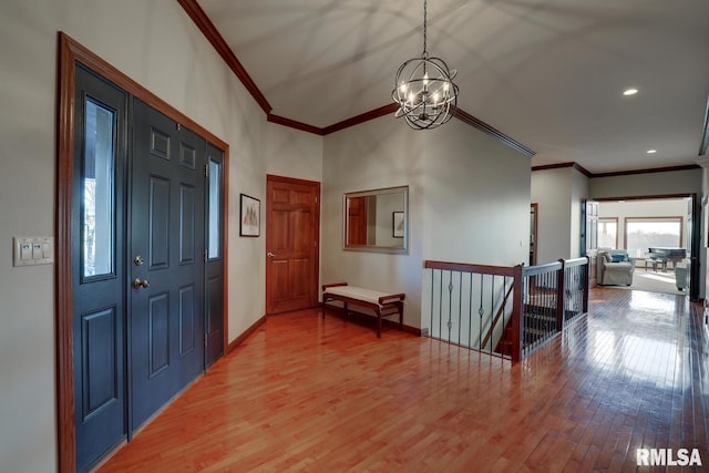 entryway with crown molding, an inviting chandelier, and hardwood / wood-style flooring