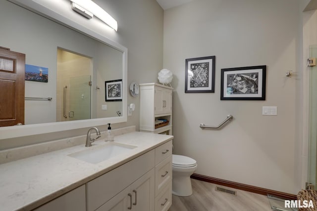 bathroom featuring vanity, hardwood / wood-style floors, an enclosed shower, and toilet