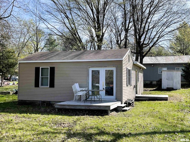 back of property with a wooden deck, an outdoor structure, and a lawn