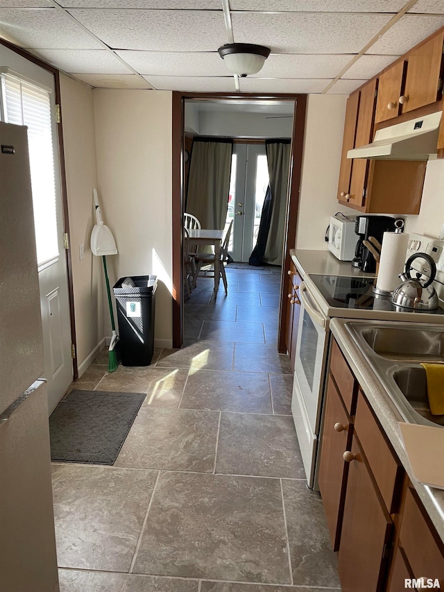 kitchen with dark tile flooring, french doors, white appliances, and a drop ceiling