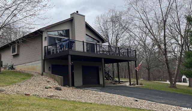 rear view of house featuring a garage, a wooden deck, and a lawn