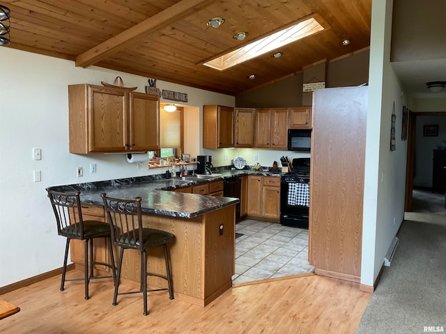 kitchen with kitchen peninsula, light hardwood / wood-style flooring, black appliances, wood ceiling, and a breakfast bar