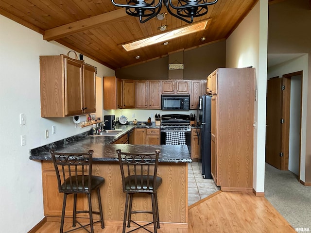 kitchen with kitchen peninsula, light hardwood / wood-style floors, black appliances, wood ceiling, and vaulted ceiling with skylight