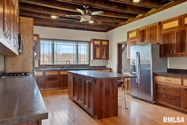 kitchen featuring a center island with sink, a kitchen bar, appliances with stainless steel finishes, ceiling fan, and sink