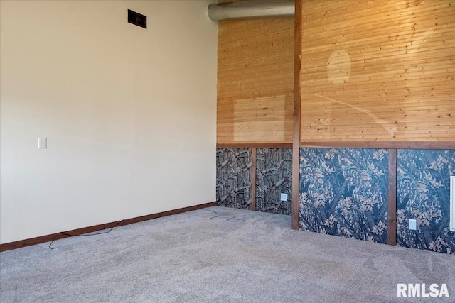 spare room featuring carpet floors and wood walls