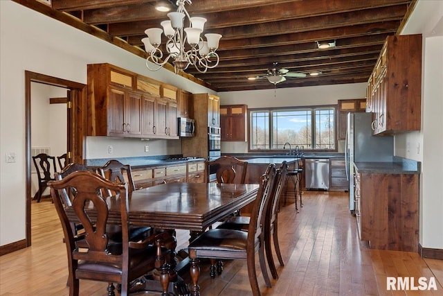 dining room featuring beam ceiling, light hardwood / wood-style floors, sink, and ceiling fan with notable chandelier