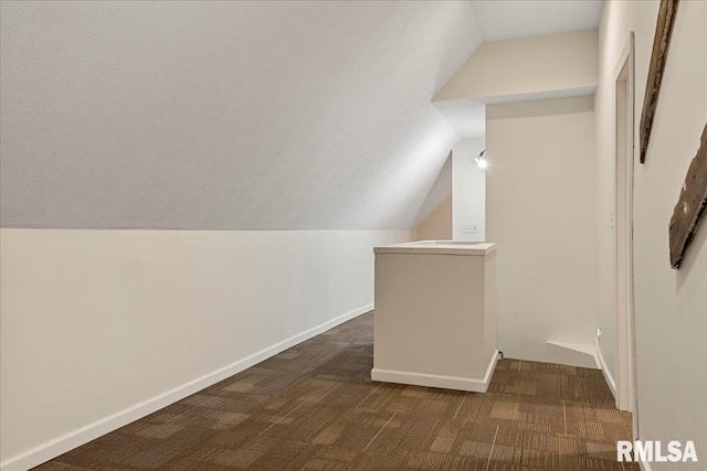 bonus room with lofted ceiling and dark colored carpet