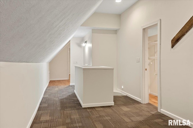 additional living space featuring lofted ceiling and dark colored carpet