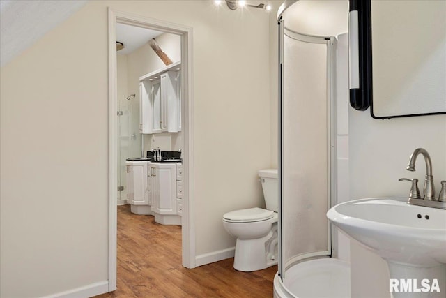 bathroom with sink, a shower with door, toilet, and hardwood / wood-style flooring