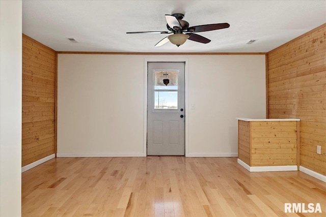 foyer entrance featuring ceiling fan, hardwood / wood-style floors, wooden walls, and crown molding