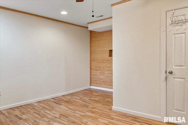 spare room featuring light hardwood / wood-style flooring, wooden walls, and crown molding