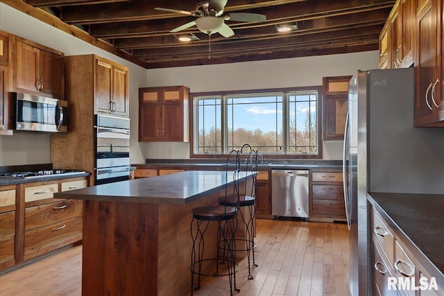 kitchen with stainless steel appliances, sink, ceiling fan, light hardwood / wood-style floors, and a kitchen island