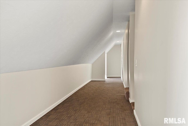 additional living space featuring lofted ceiling and dark colored carpet