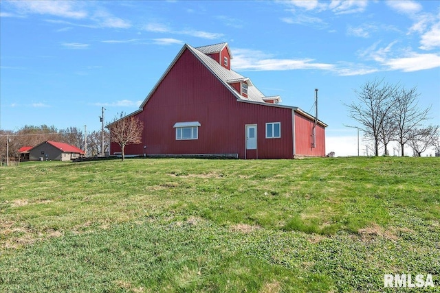 view of side of home featuring a yard and an outbuilding