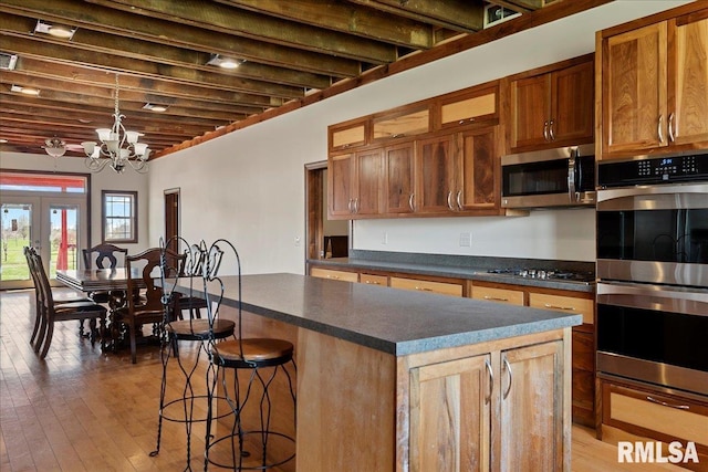 kitchen with a kitchen breakfast bar, stainless steel appliances, a center island, pendant lighting, and an inviting chandelier