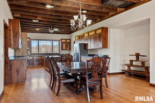 dining area with ceiling fan with notable chandelier, light hardwood / wood-style floors, beamed ceiling, and sink