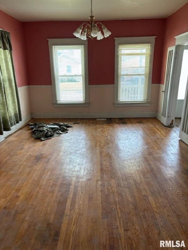 empty room with a notable chandelier and hardwood / wood-style floors