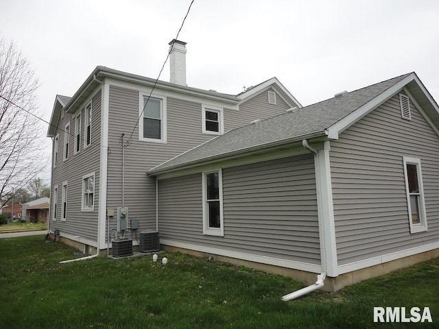 back of property with central air condition unit and a lawn