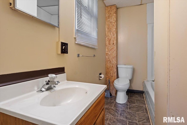 bathroom featuring vanity, toilet, and a washtub