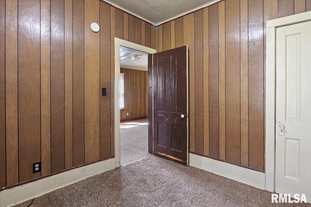 hall featuring wood walls, dark carpet, and ornamental molding