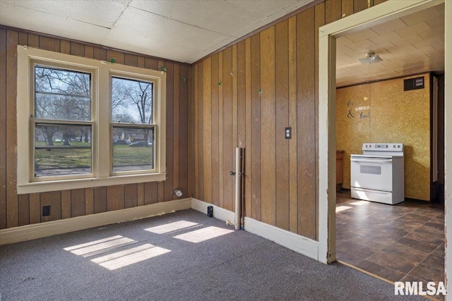 spare room featuring dark colored carpet and wood walls