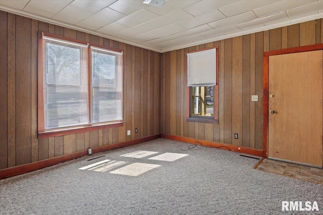 unfurnished room featuring crown molding, wooden walls, and carpet floors