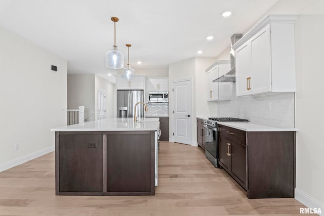 kitchen with a center island with sink, light hardwood / wood-style floors, stainless steel appliances, and tasteful backsplash