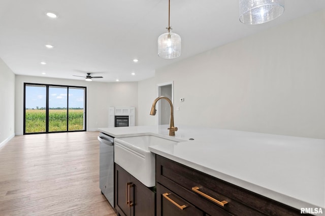 kitchen featuring light wood-type flooring, sink, hanging light fixtures, ceiling fan, and stainless steel dishwasher