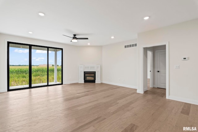 unfurnished living room featuring light wood-type flooring, ceiling fan, and a tile fireplace