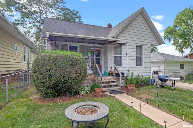 bungalow featuring a front lawn and an outdoor fire pit